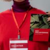 Close-up of a volunteer holding an eco volunteering brochure with a red tag.