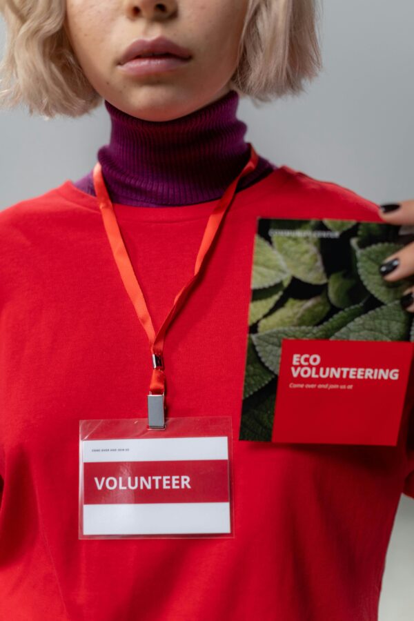 Close-up of a volunteer holding an eco volunteering brochure with a red tag.