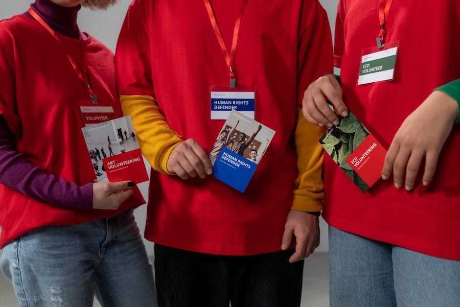 Volunteers in red shirts holding informational booklets on art and eco volunteering.
